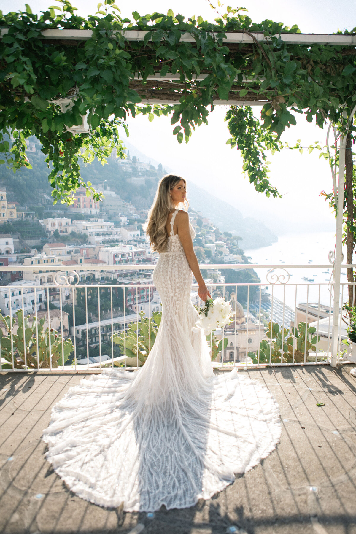 Bride and groom walking hand in hand on Italian terrace with sea view – romantic wedding portrait in Positano