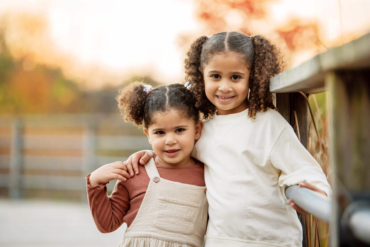 Sisters hugging with the golden light behind them for their Burlington fall family photos 