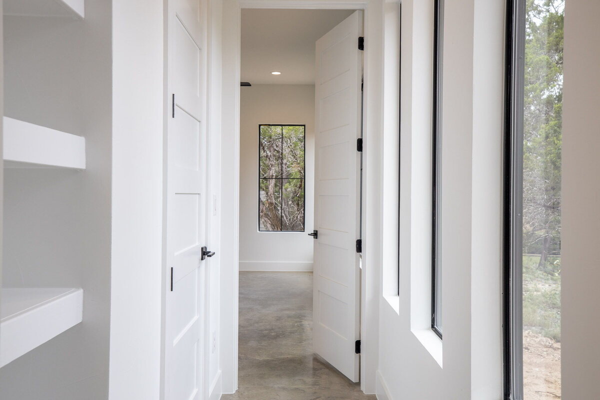 hallway with white walls, black windows and concrete floors