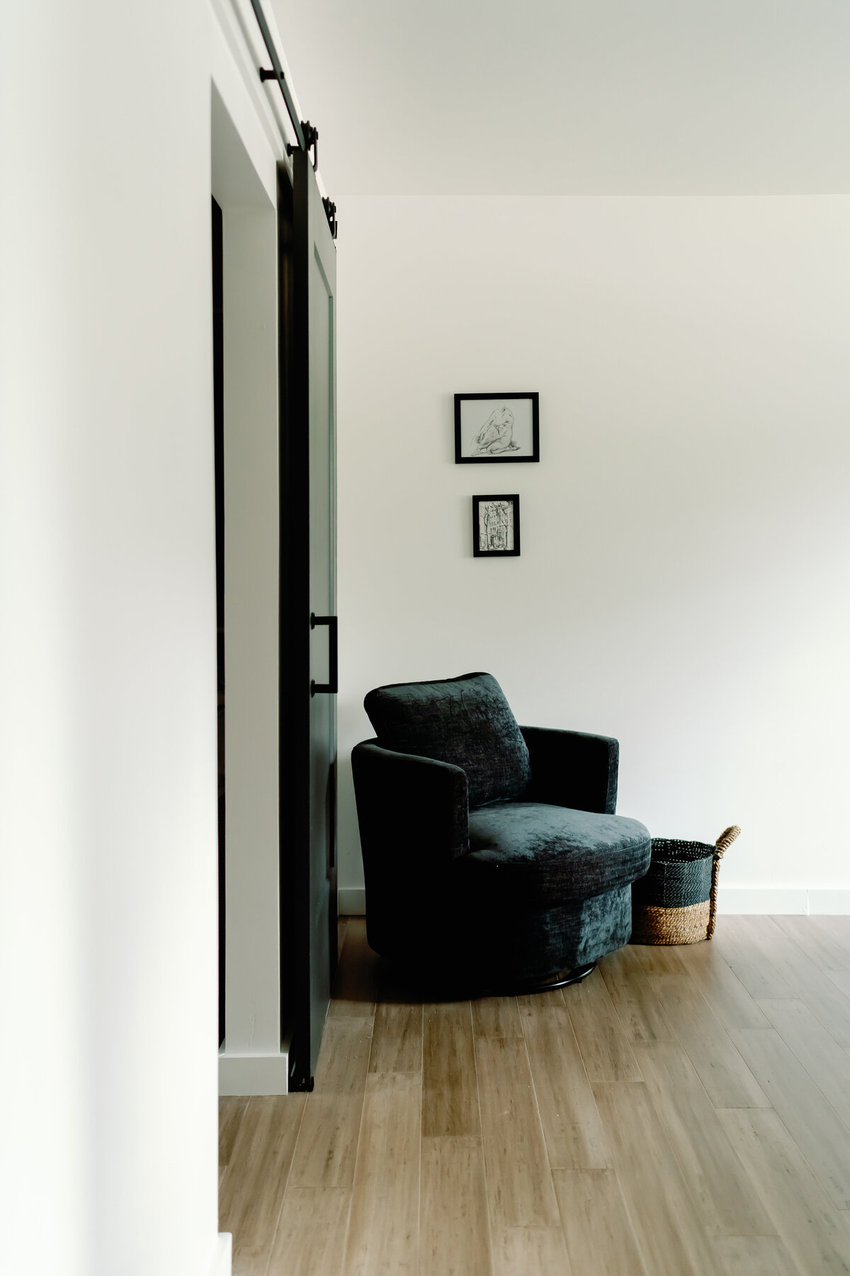 black swivel accent chair in main bedroom with wood floors, black door and white walls