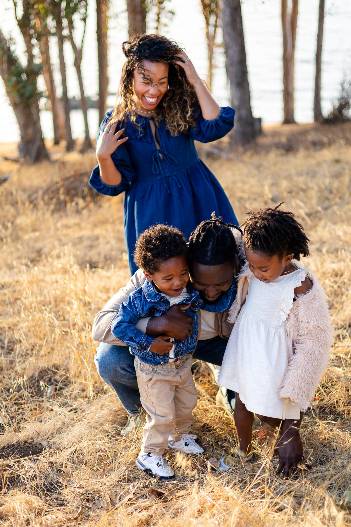 Father hugging children as mother smiles nearby in golden light, Bay Area Family Portfolio – Ellobelle Photography