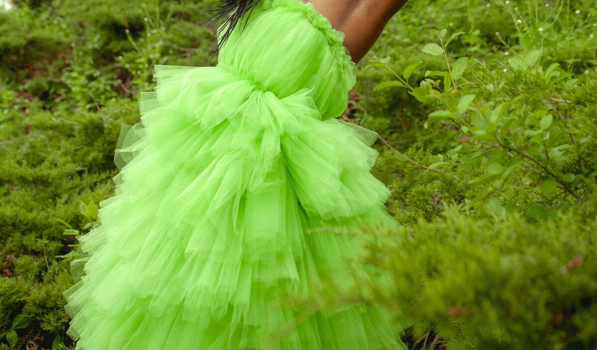 Black woman in a green dress posing in the forest