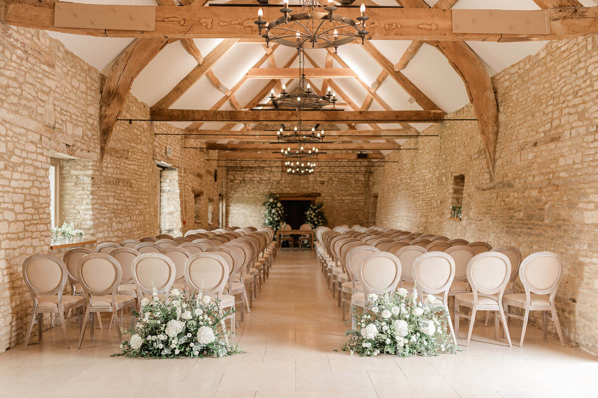 Elegant barn ceremony at Caswell House with floral arrangements and lime Louis chairs