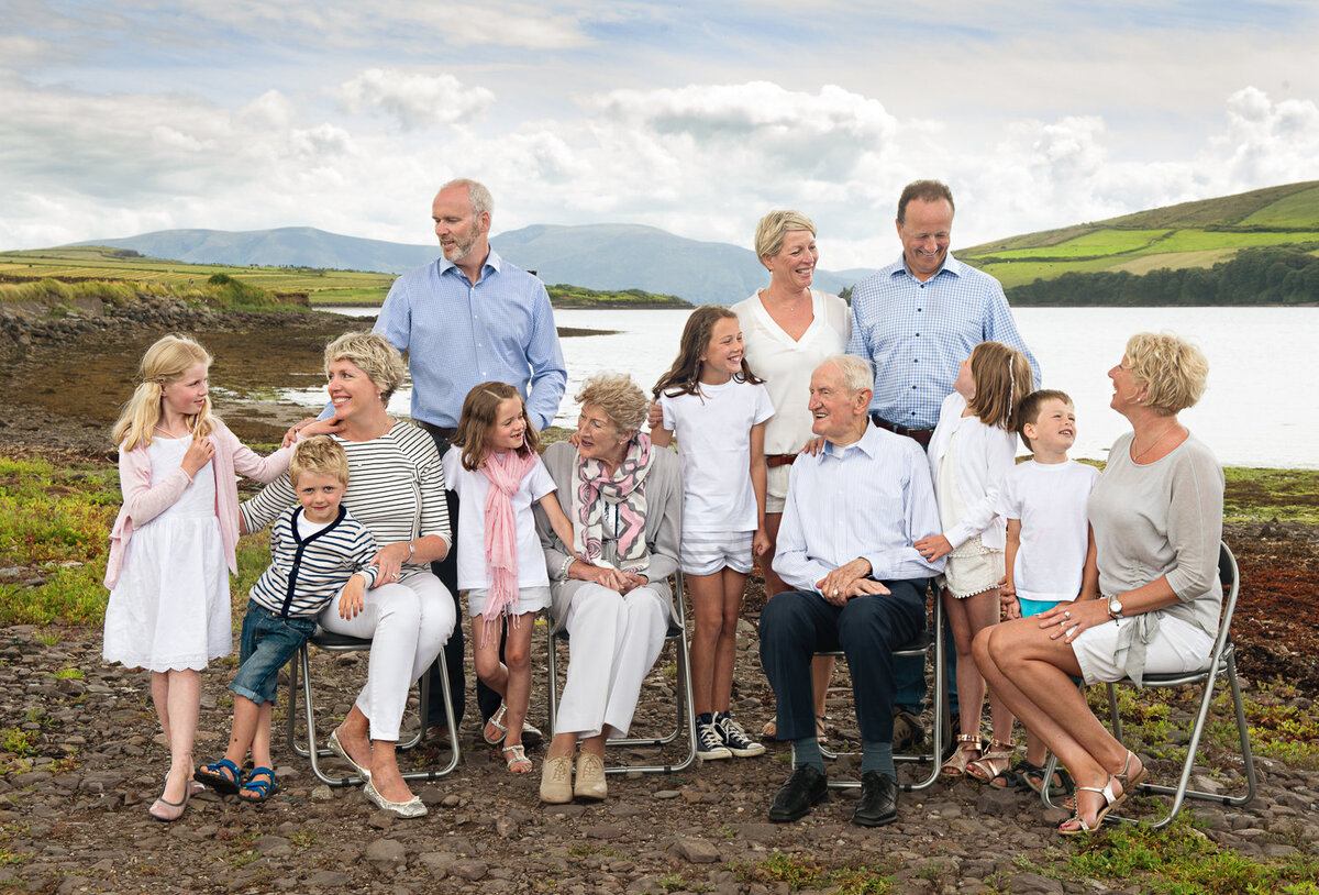 portrait of three generations of a family sitting on a beach in Dingle, talking and laughing with each other