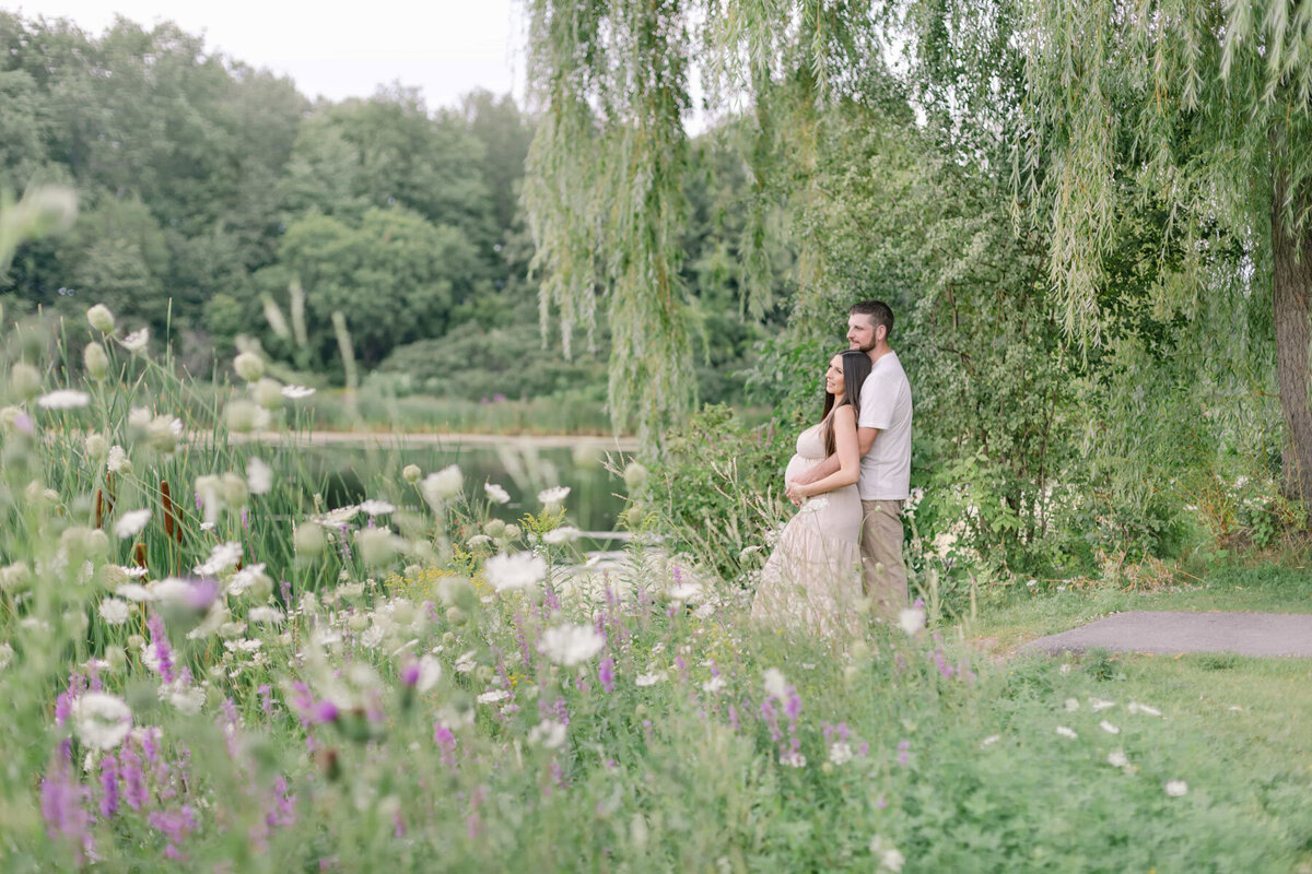 Orange County Maternity Photographer - couple enjoying the view of a calm pond surrouded by greenery