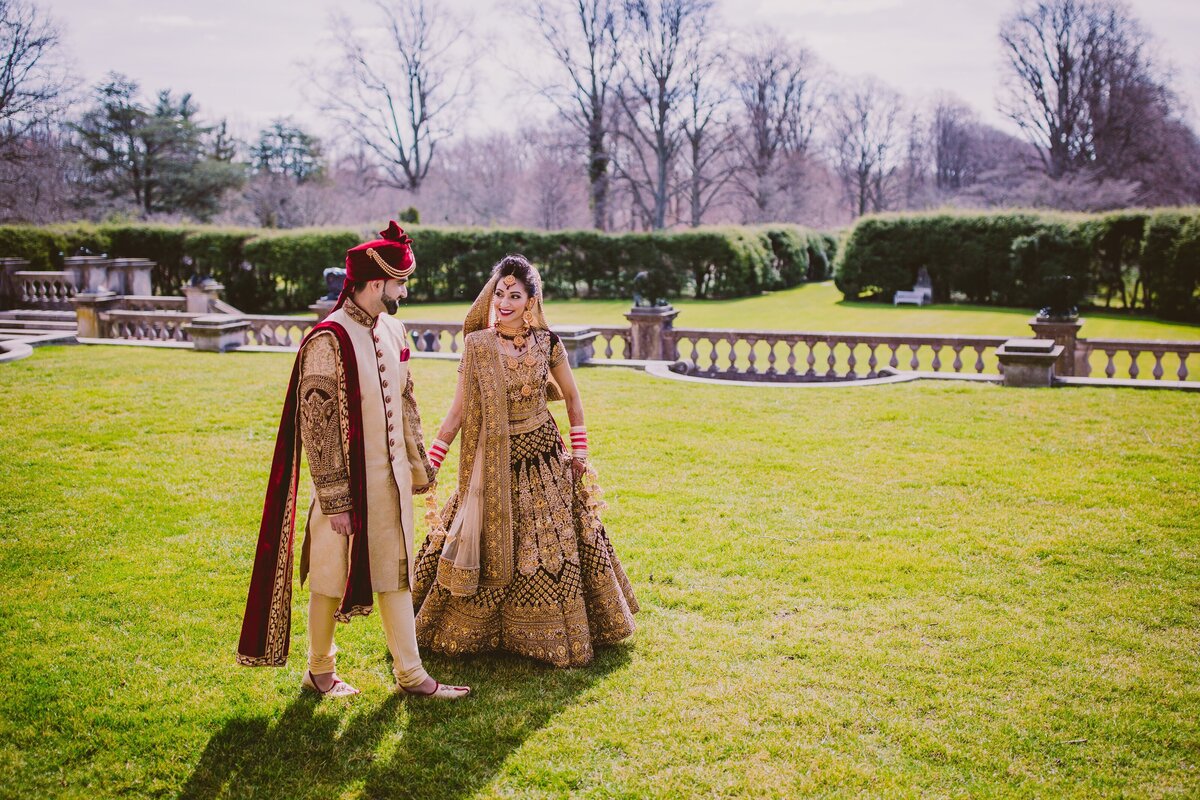 Indian hindu bride and groom walking together on the wedding day at the old westbury gardens in ny