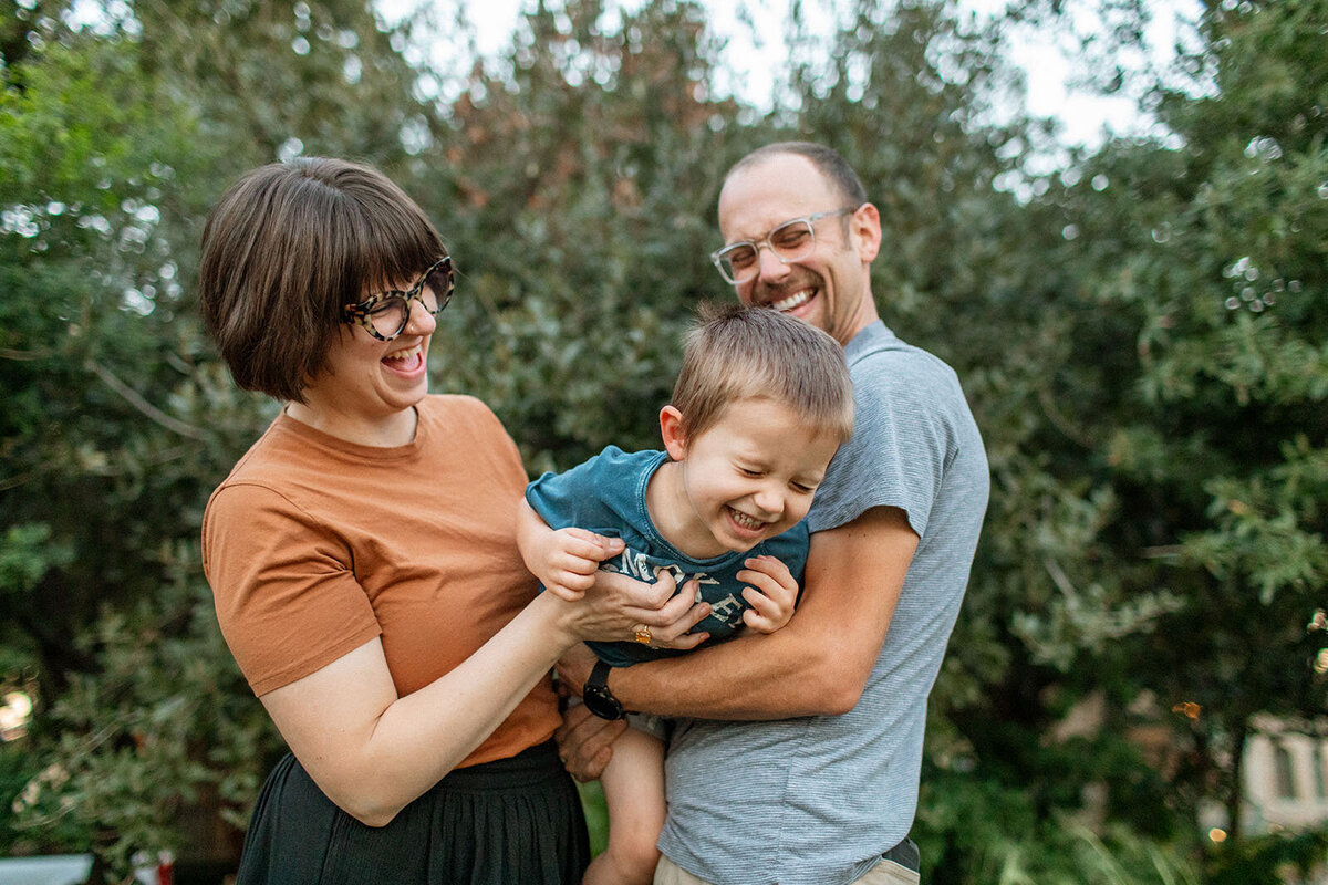 Candid outdoor portrait of a mom, dad, and child laughing together, captured by San Antonio photographer Sara James.