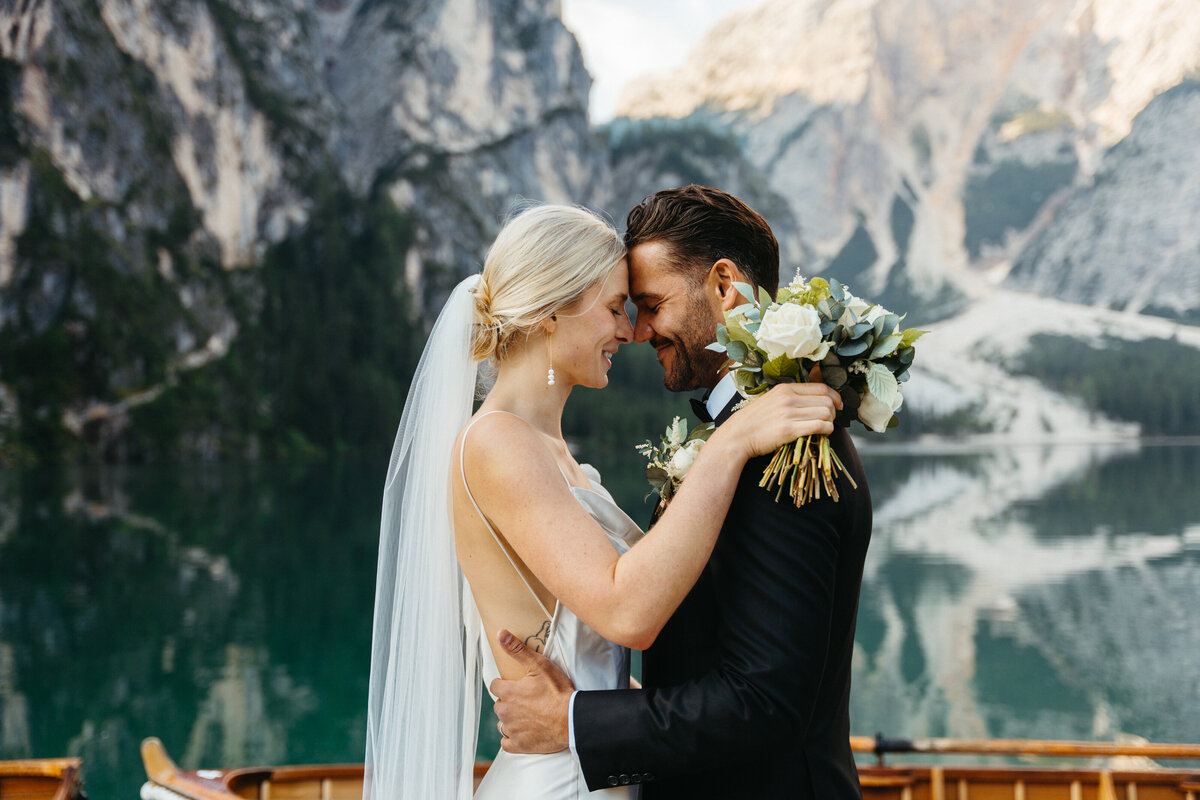 Couple holding bouquet during intimate embrace at Lago di Braies