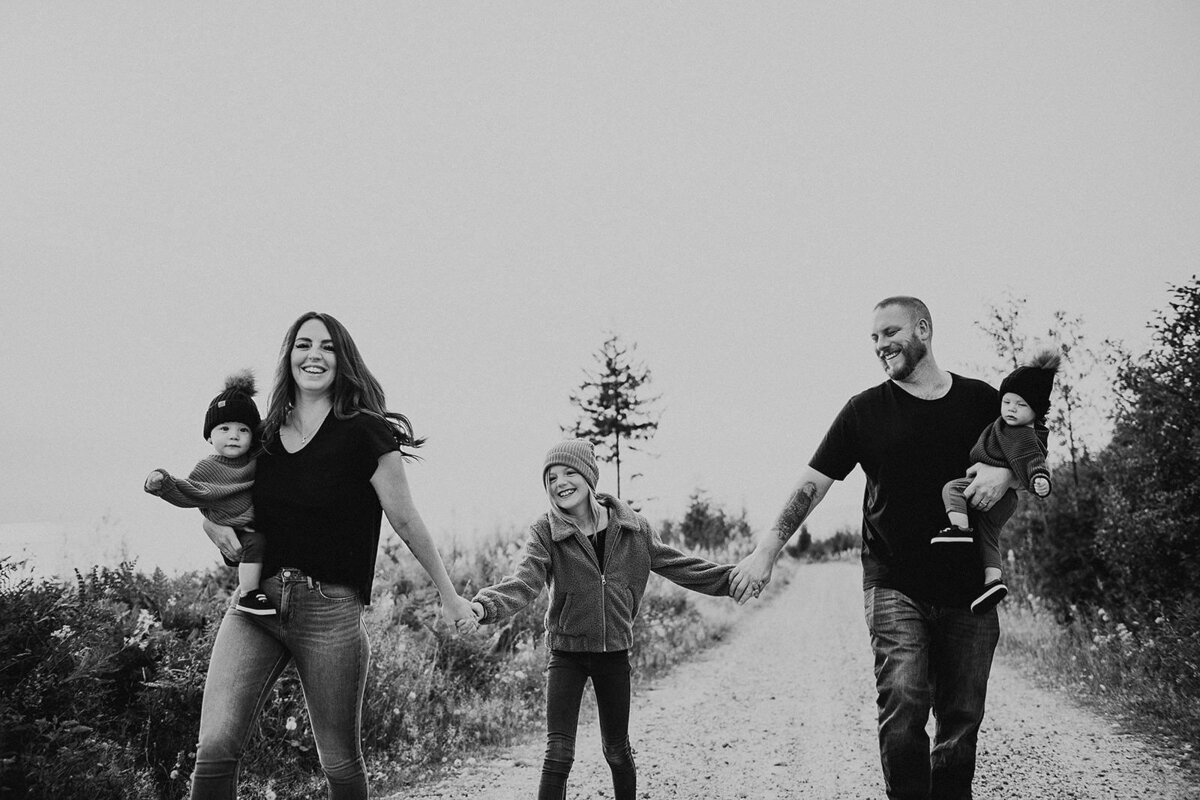 Smiling family walking down a mountain road at their family session in Gibsons  B.C