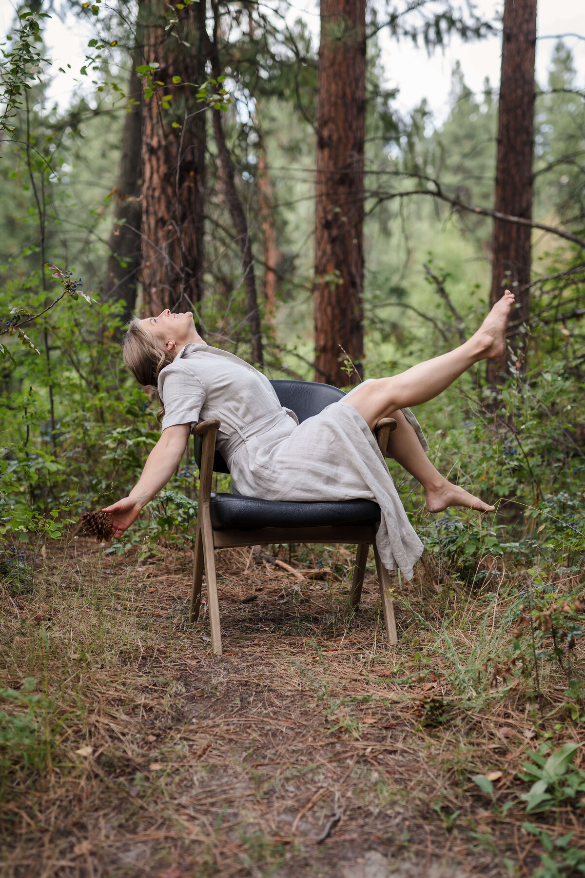 woman leaning back in chair in the forest for outdoor branding photoshoot