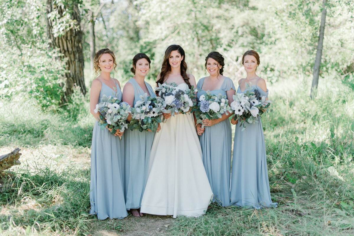 Classic and romantic bride with her bridal party, bridesmaids in blue dressed with white and blue bouquets, captured by Kaity Body Photography, elegant film inspired wedding photographer in Calgary, Alberta. Featured on the Bronte Bride Vendor Guide.
