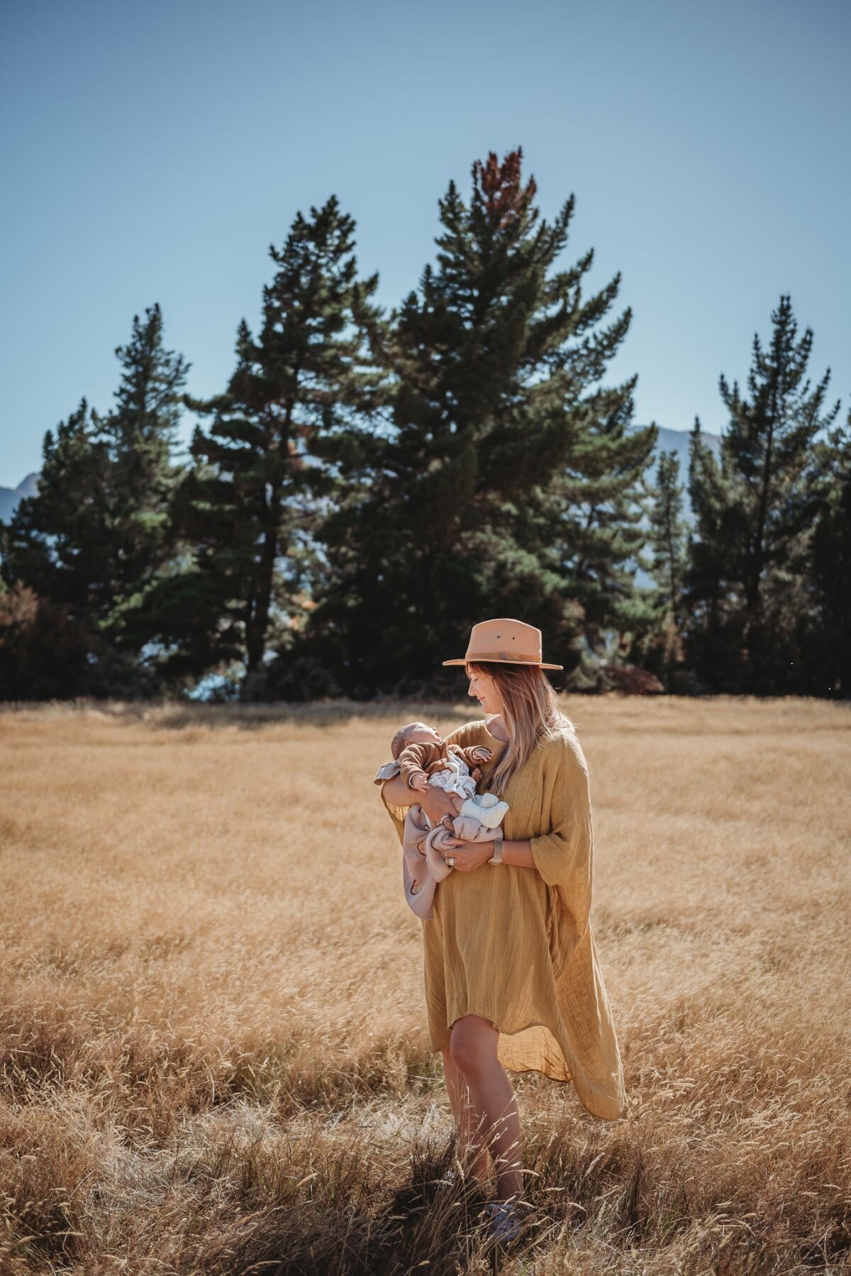 a mum standing in the field in lake hawea with her newborn baby