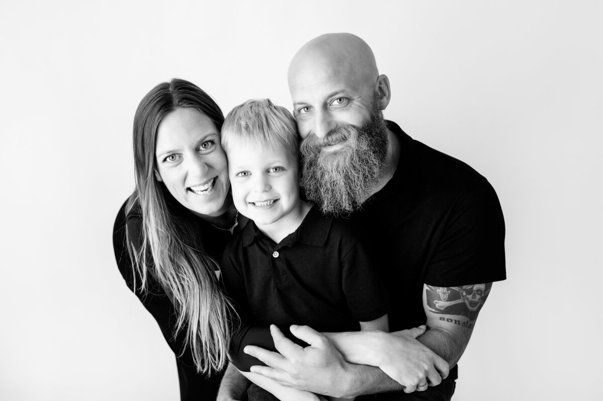 smiling family of three black and white studio portrait