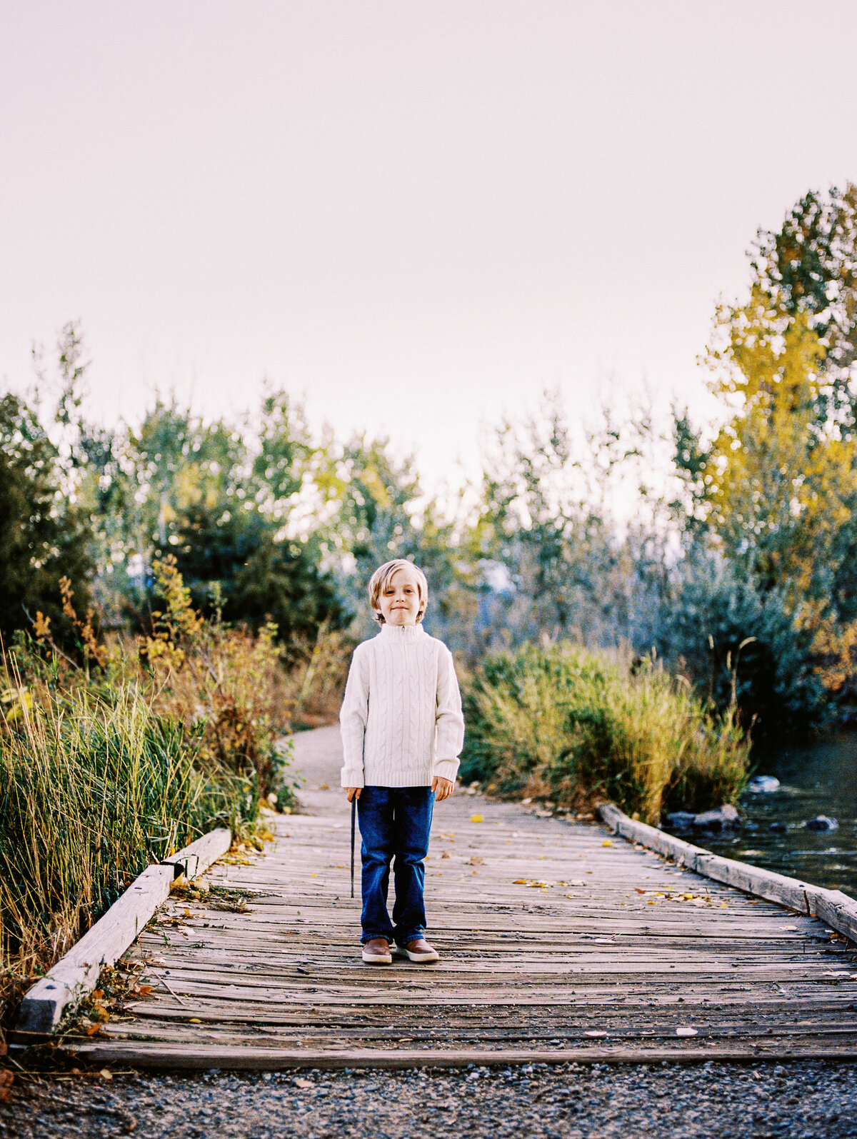 boy stands on a wooden bridge in the fall