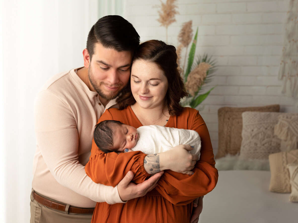 mom and dad holding newborn son for boho style photoshoot