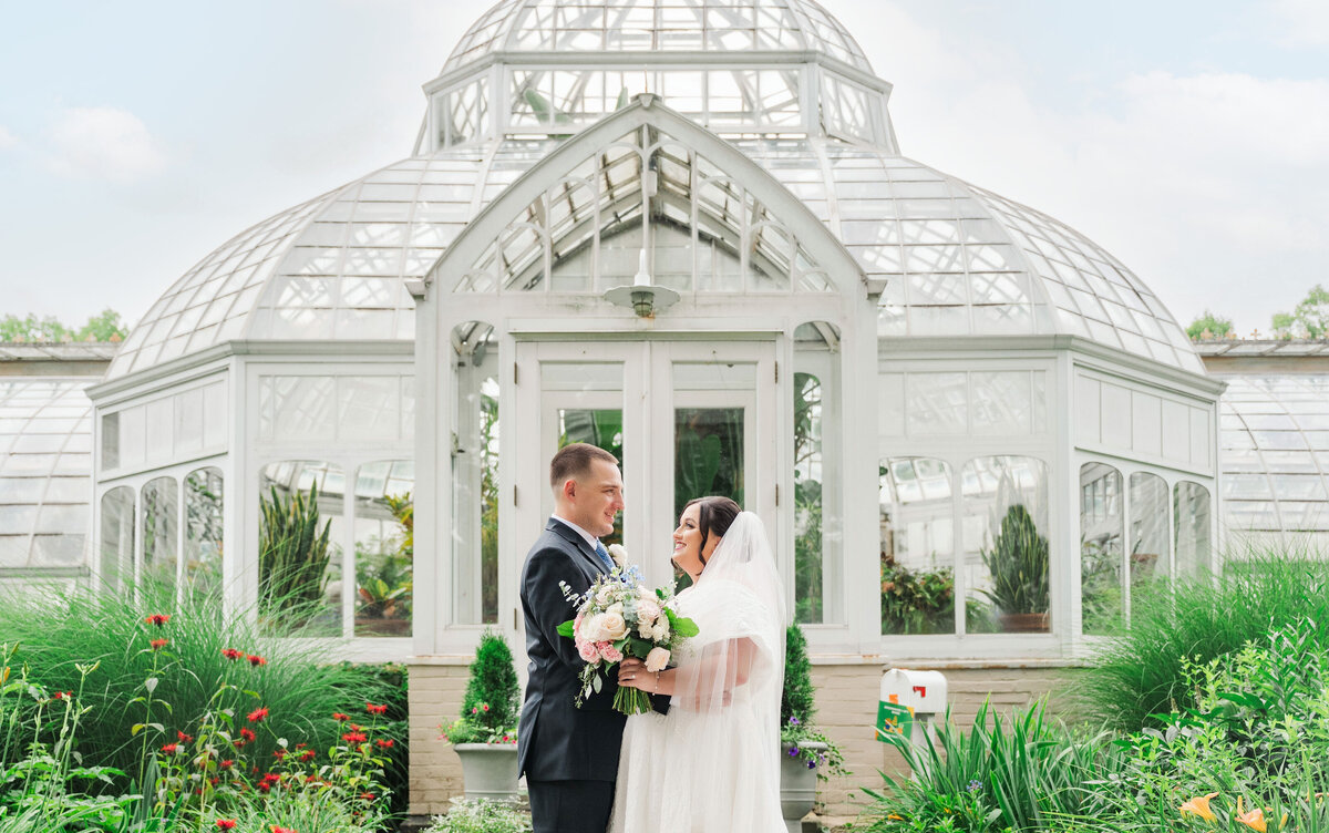 wedding couple posing for pictures at the greenhouse at Frick Museum