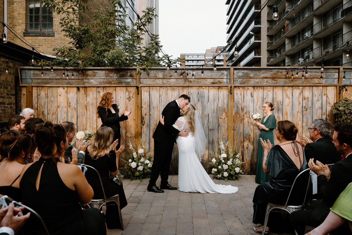 Bride and groom shares a kiss at the altar as the guests clap their hands