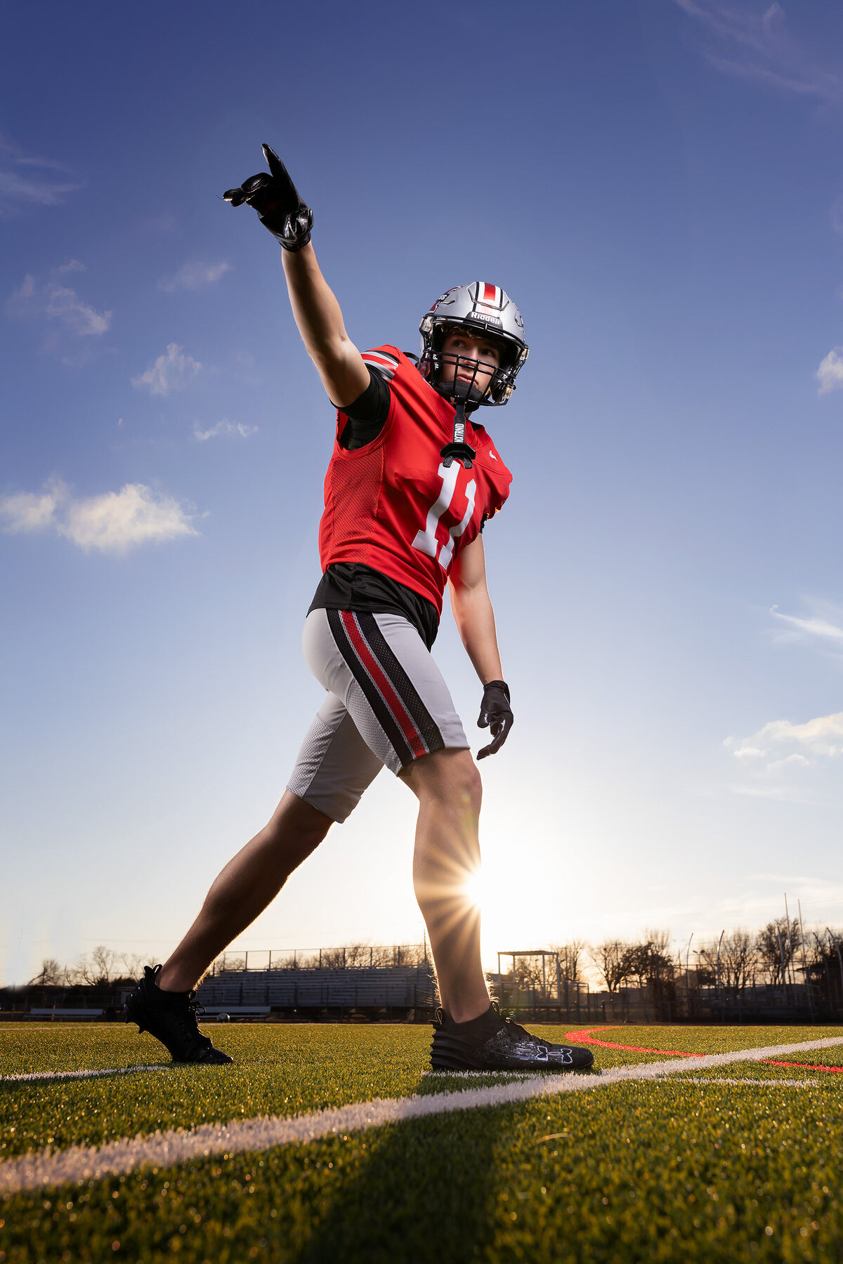 A senior football player strikes a powerful pose, captured in dynamic senior photography Dallas.