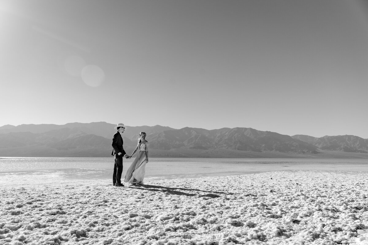 A couple holding hands and walking on a salt flat