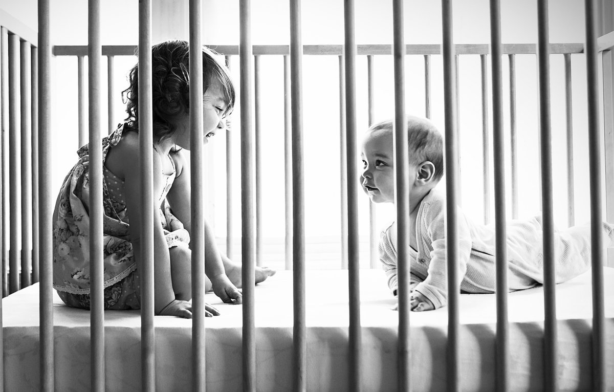 charlotte documentary photographer jamie lucido captures a beautiful candid image of children playing in their crib