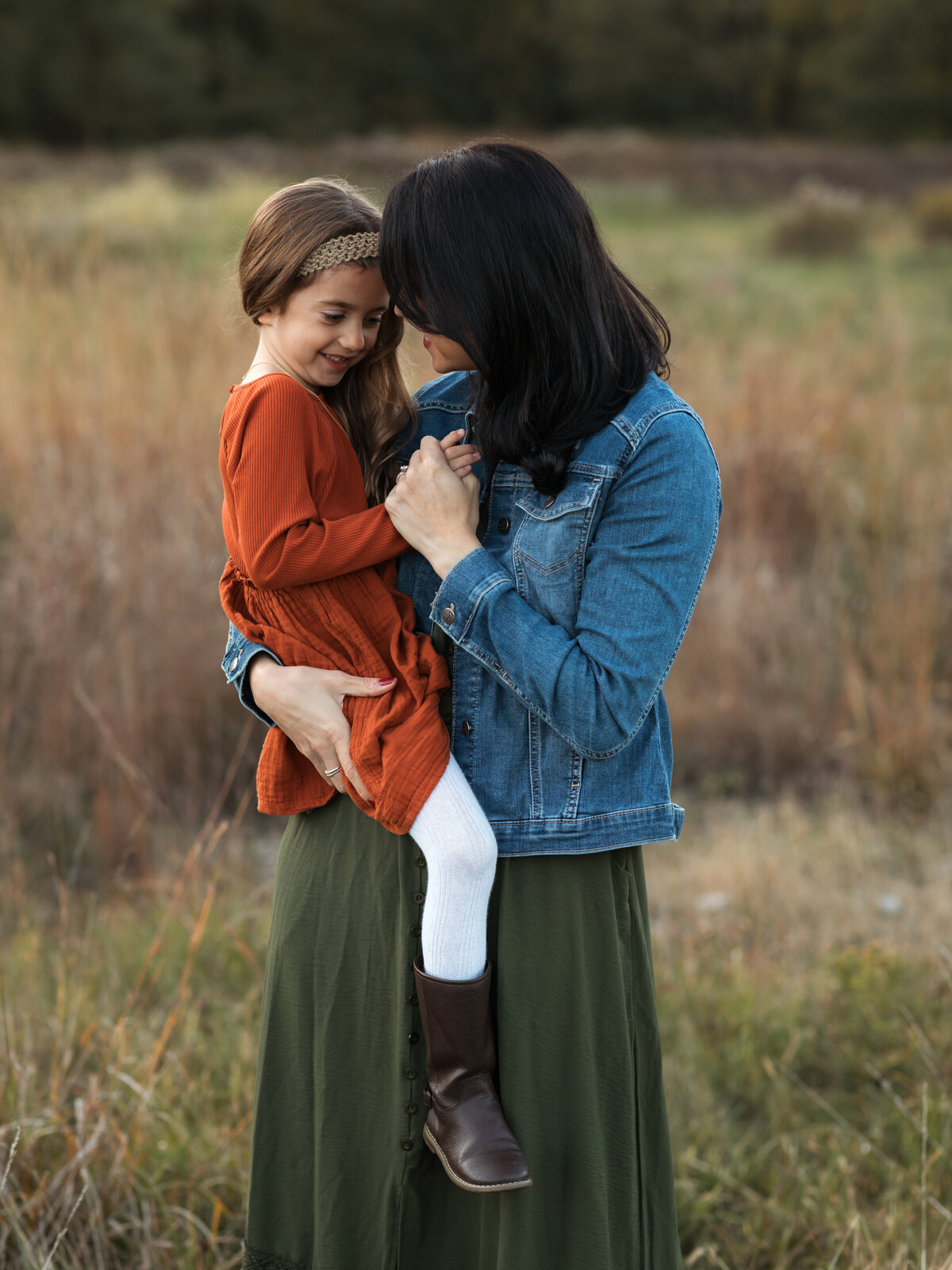 mom holding daughter in field for family photos