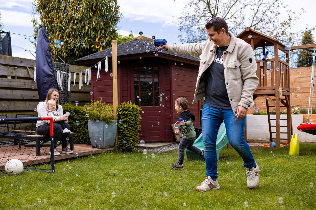 gezinsfoto thuis in achtertuin spelen met bellenblaas