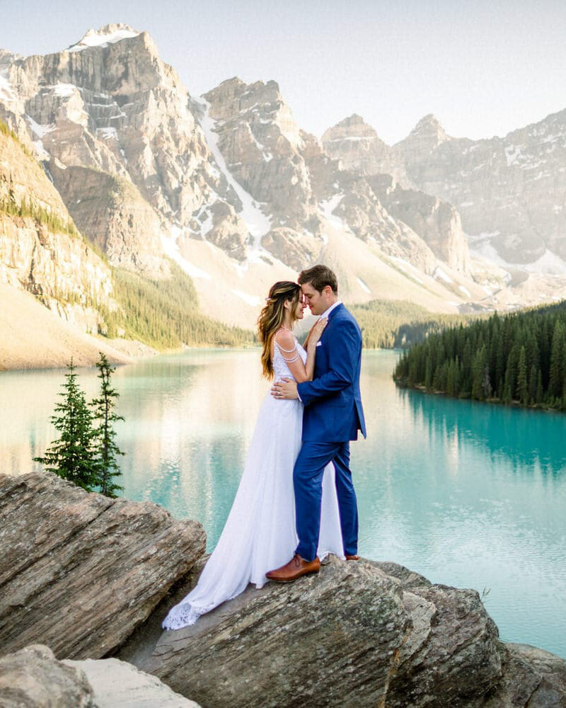 This breathtaking photograph captures the bride and groom holding each other at Moraine Lake during their summer wedding celebration. The iconic Valley of Ten Peaks in Banff National Park creates a stunning backdrop, enhancing the beauty and romance of their special day.