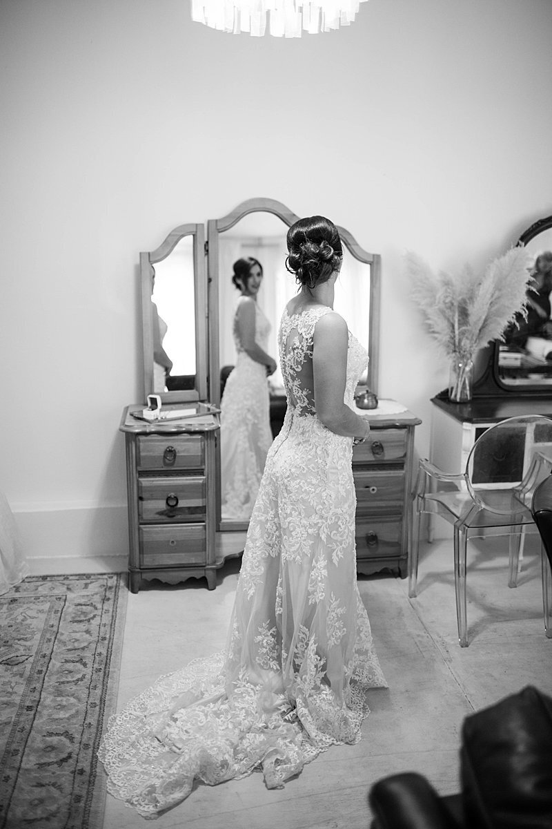 Bride looking in mirror at wedding gown