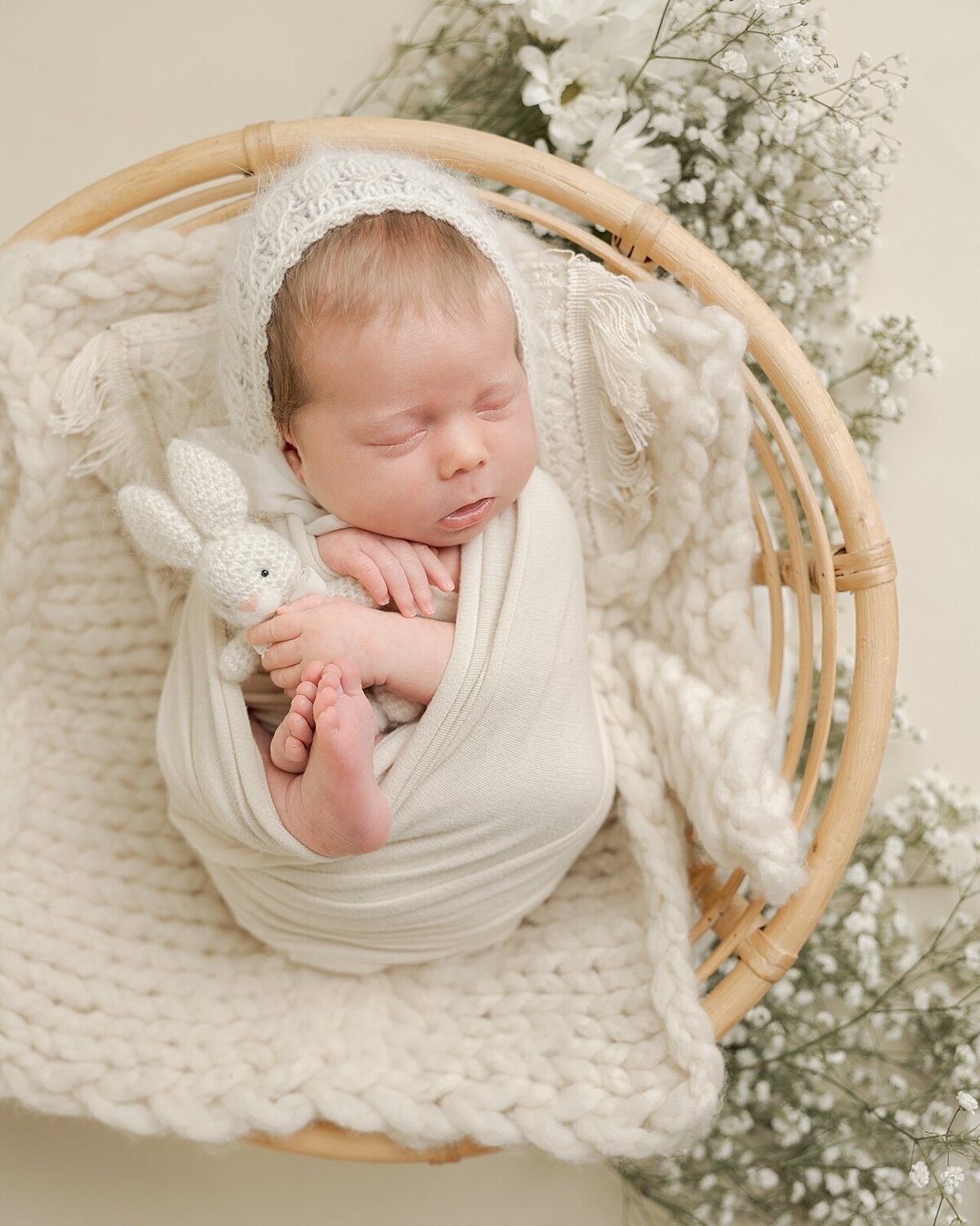 baby girl holding bunny in bowl with flowers