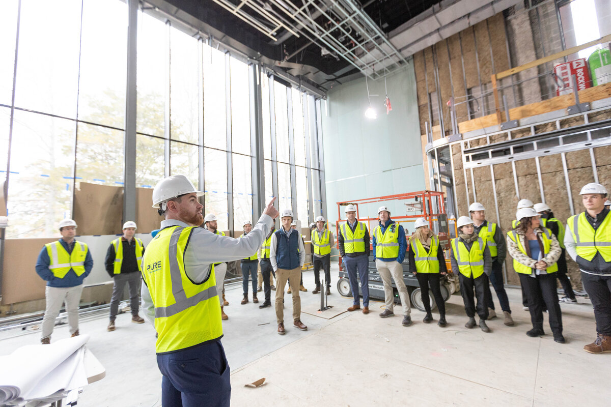 Group of construction workers reviewing industrial space with large windows