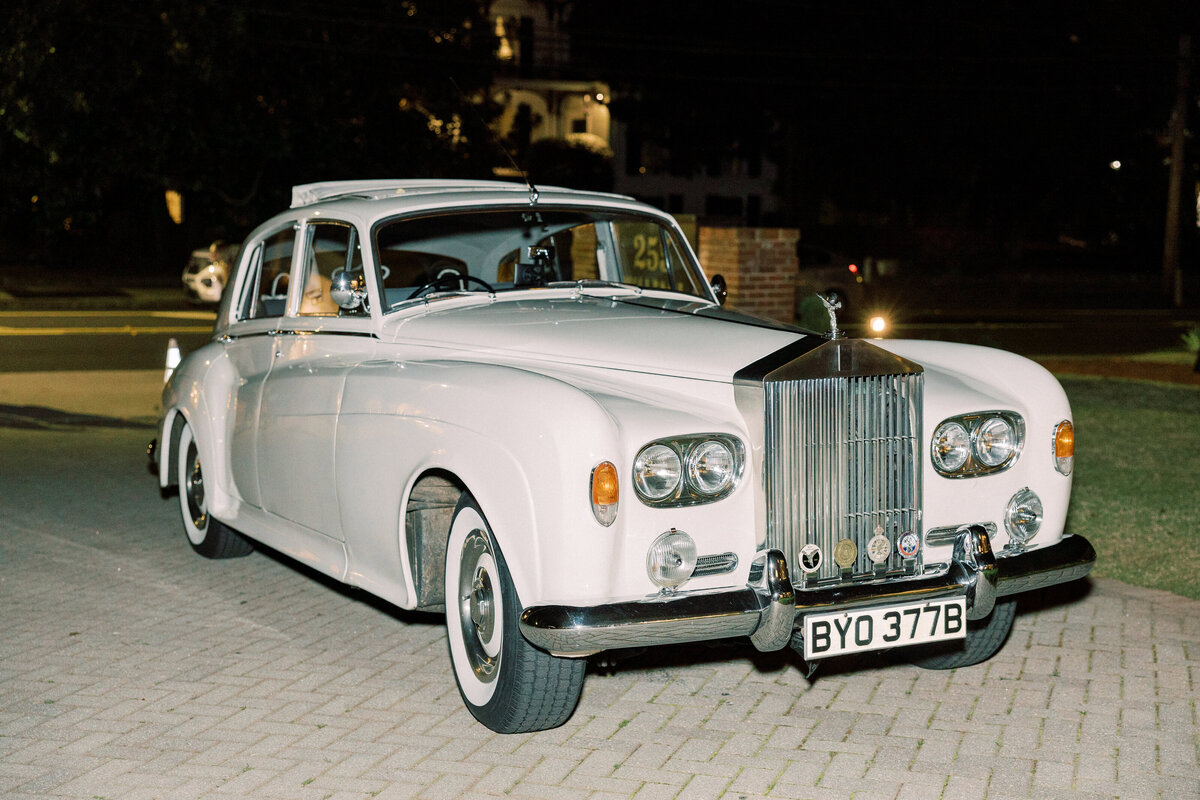 White vintage car waits outside elegant wedding