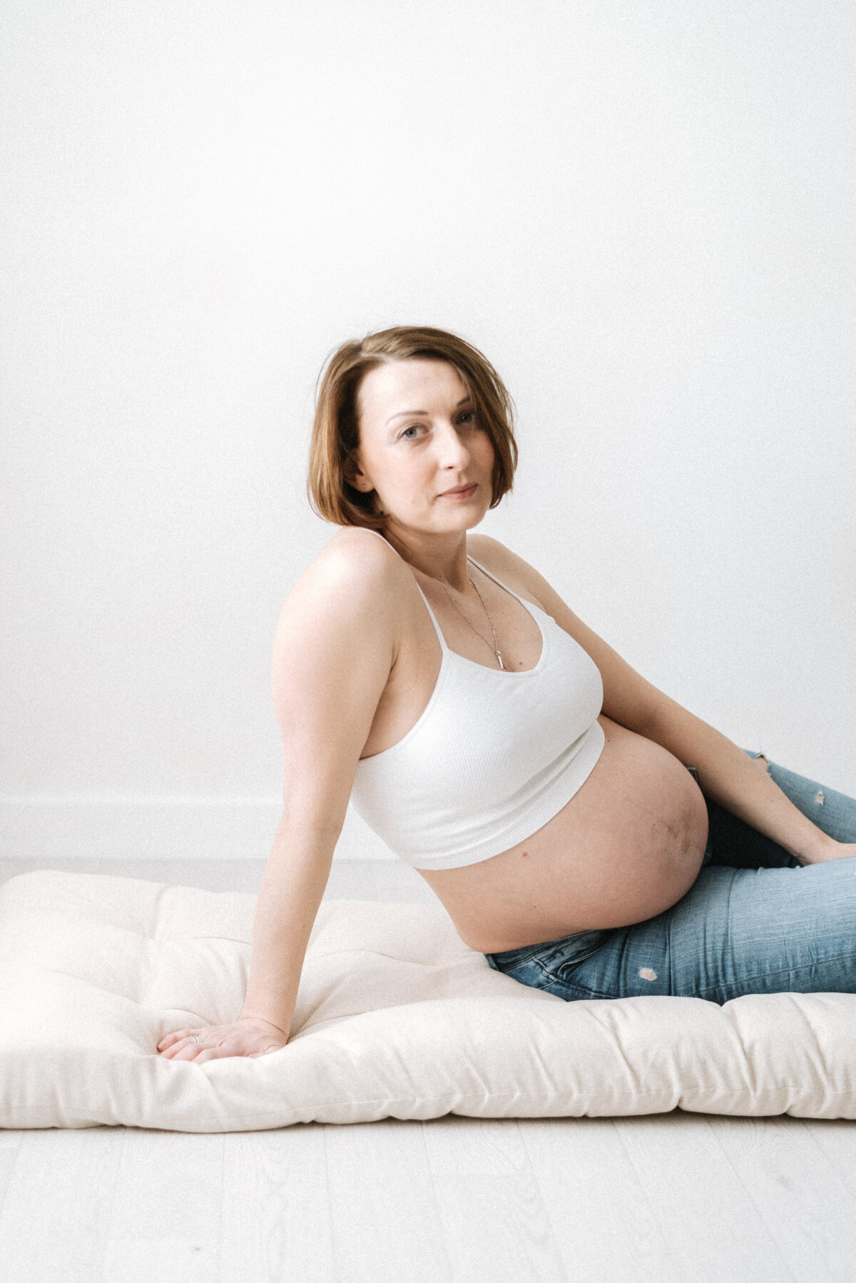 A pregnant women sitting on a cushion at maternity photoshoot in billingshurst