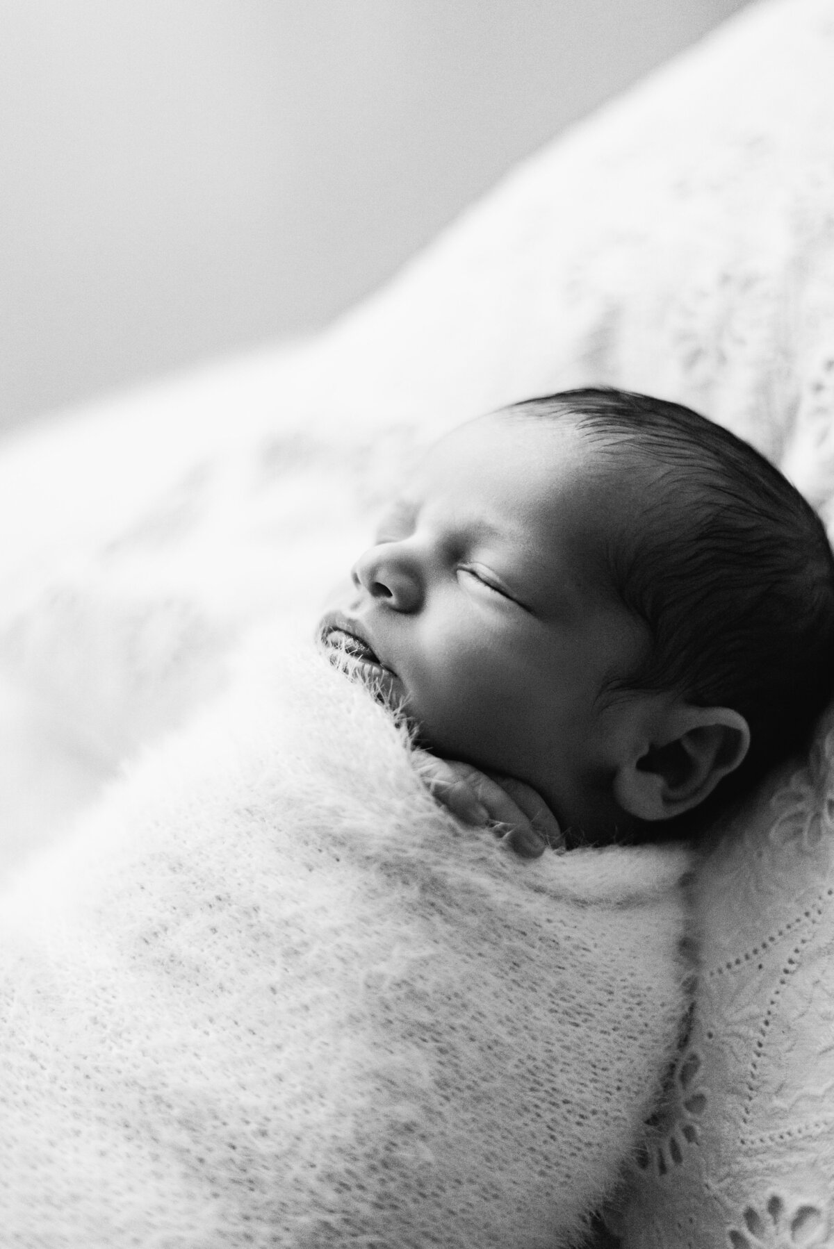 Baby boy wrapped up in a blanket sleeping at newborn photoshoot in Billingshurst