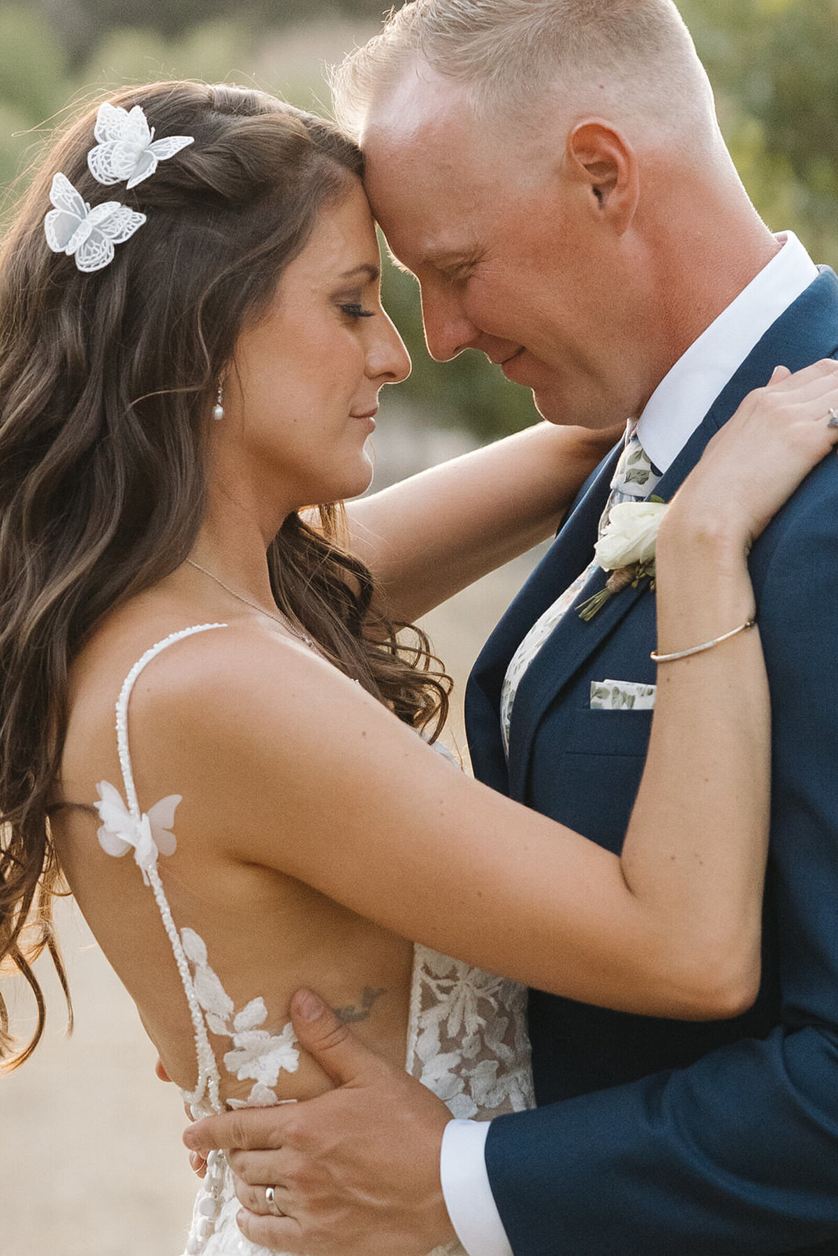 Bride and groom forehead to forehead in the orchard at sunset