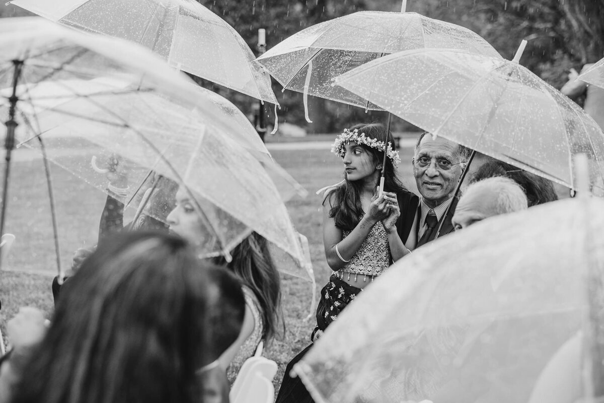 Wedding guests sitting while holding clear umbrellas 