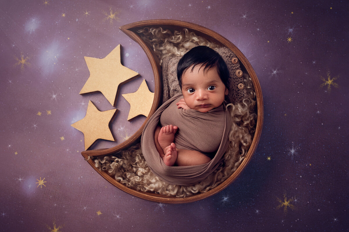 Newborn boy posed in a starry night moon prop — photographed by an Oakville newborn photographer