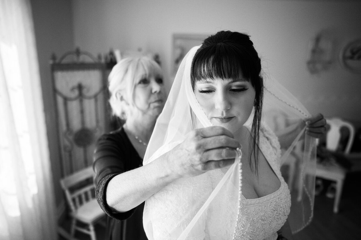 Mother of the bride places the bridal veil over her daughter