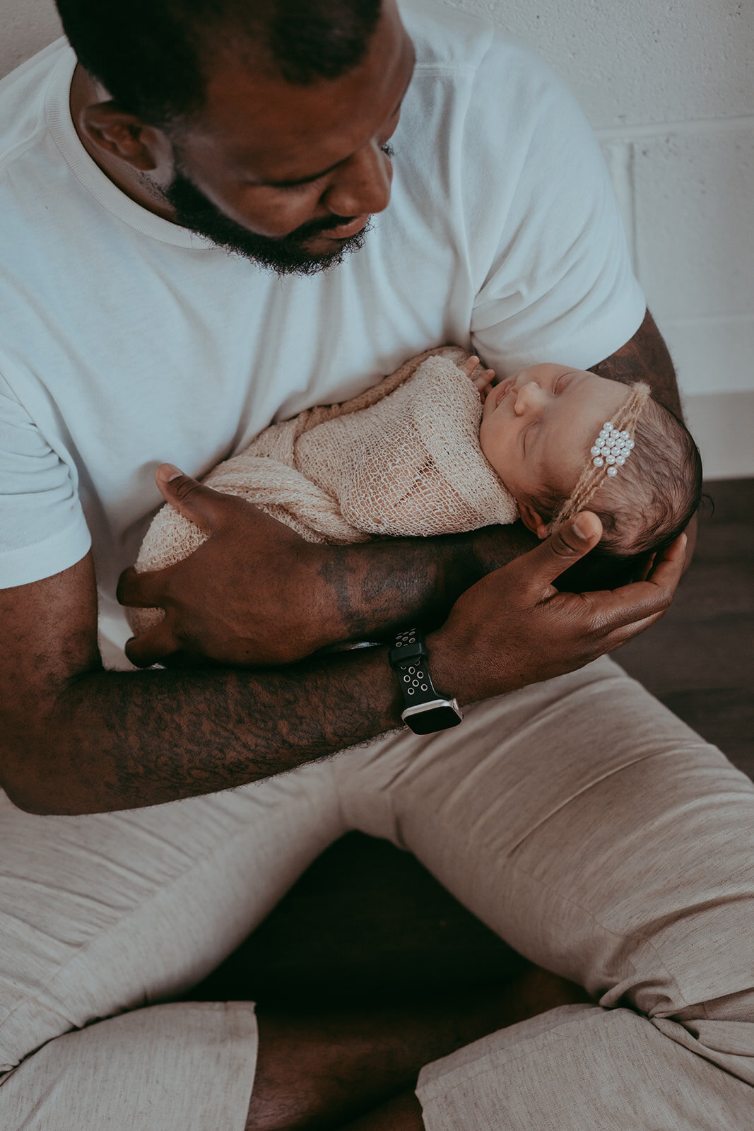 father cradles his newborn baby girl in his arms during parker colorado studio session