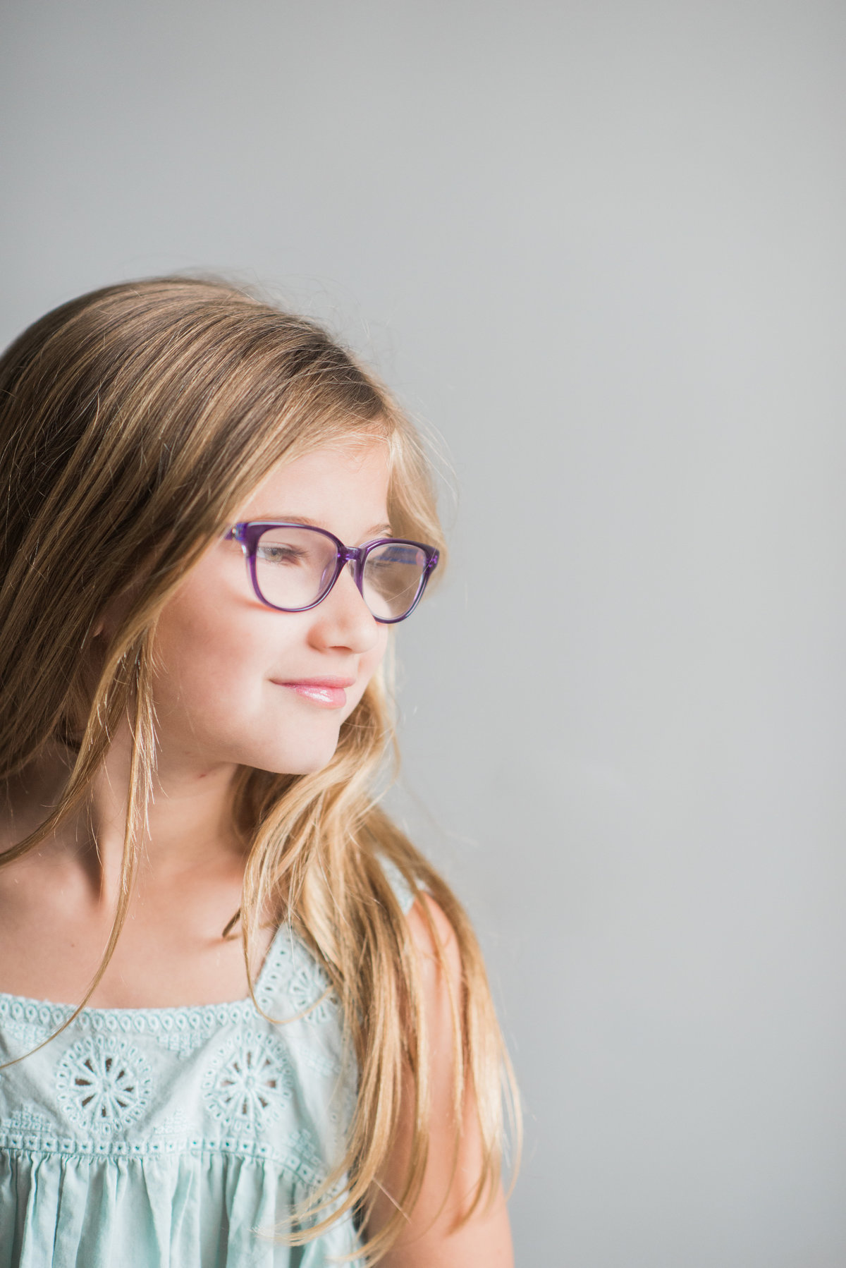 young girl in purple glasses looking away