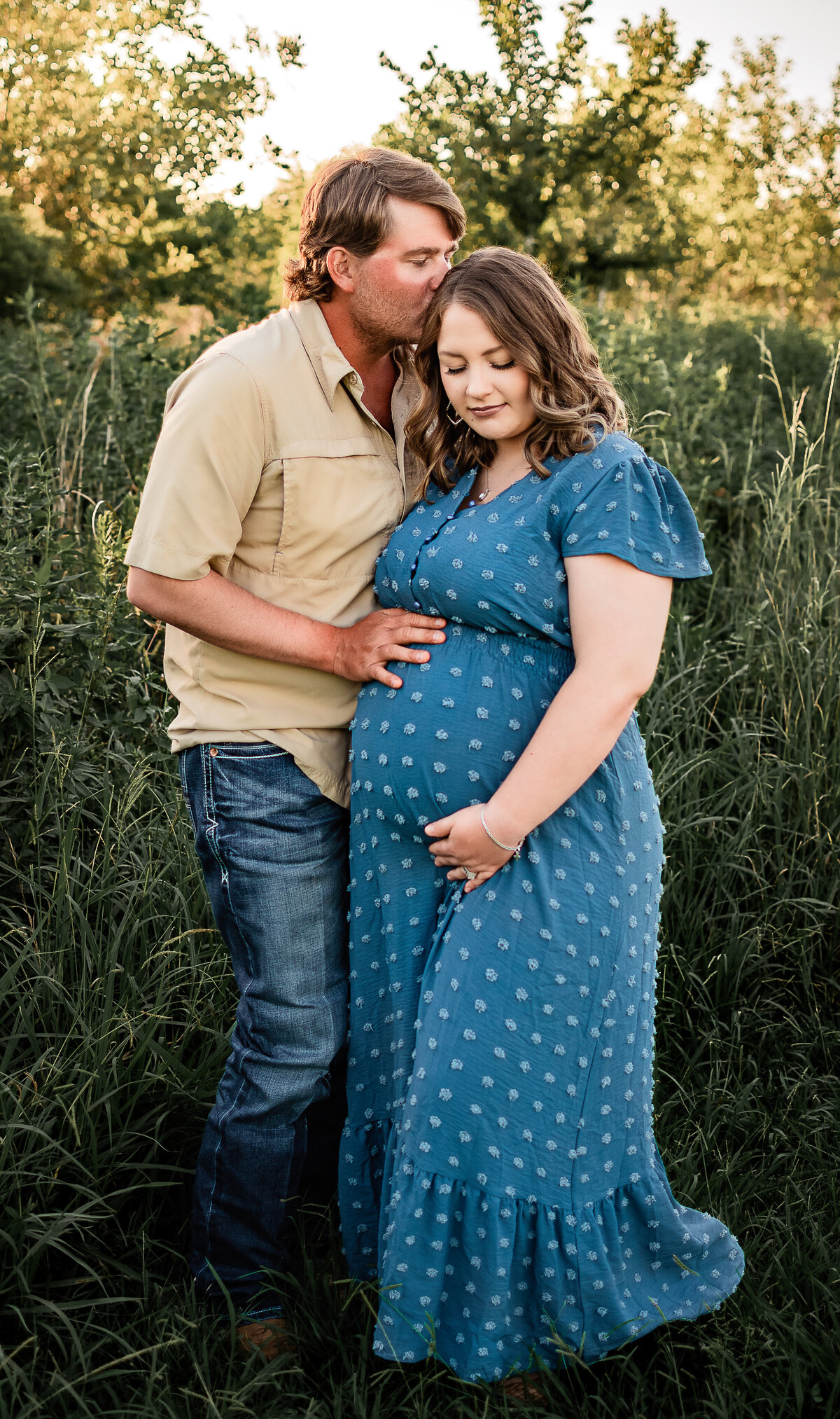 A dad to be kisses his expectant wife's head as she cradles her belly bump.
