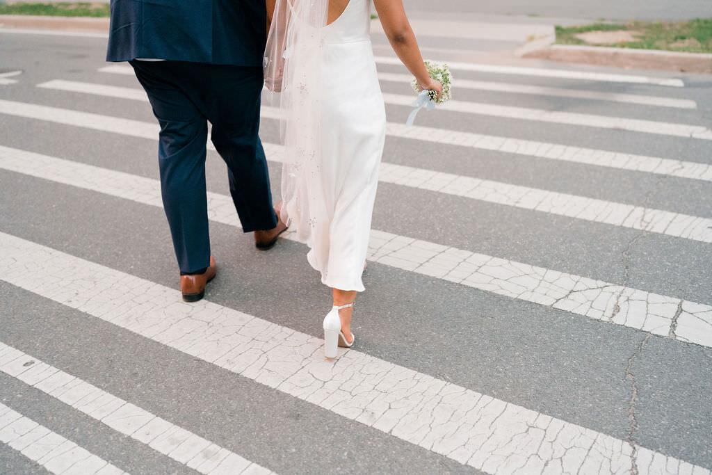 bride and grooms legs as they walk across a city street