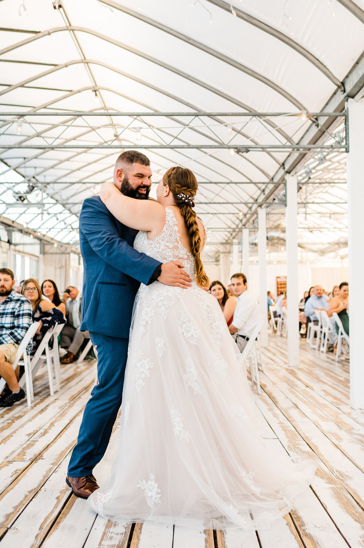 first dance between bride and groom at showalter's orchard wedding with groom smiling at his bride while everyone watches them dance for the first time as husband and wife