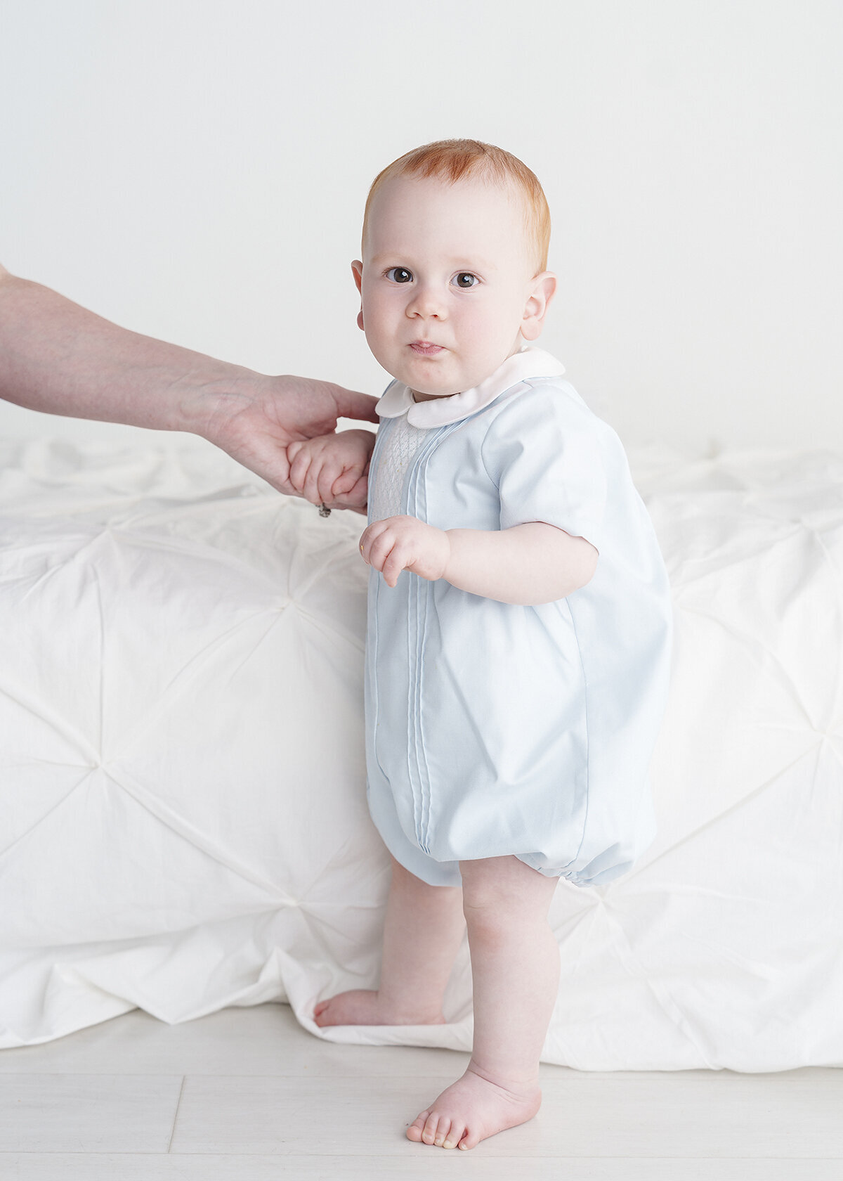 red haired 9month old baby boy wearing a feltman brother outfit photographed for his milestone session in studio