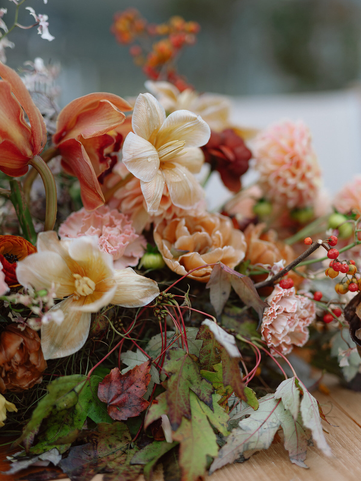 Sculptural ikebana and meadow arrangements decorate the cocktail hour for private estate wedding in Tennessee hills.Clear top tent build out for fall wedding reception in Tennessee hills.  Trailing bar arrangements and floral meadow centerpieces for autumnal wedding reception. Orchids, bittersweet berries, butterfly ranunculus, and tulips are highlighted. Artistic fall color palette in copper, gold, ruby, lavender, and rust. Design by Rosemary & Finch Floral Design in Nashville, TN.