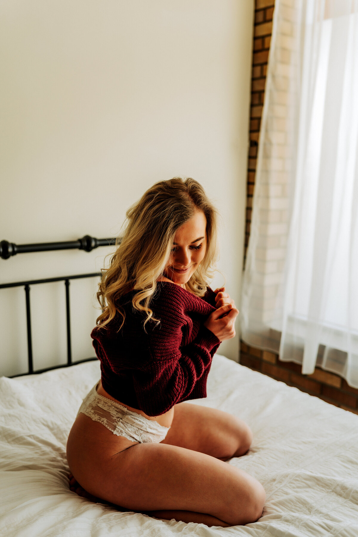 woman tugging on sweater and looking down on bed