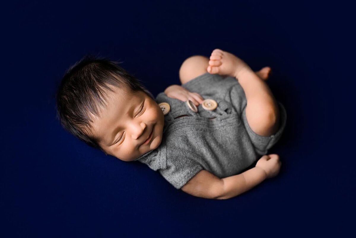 mobile-in-home-newborn-photography-vancouver-fraser-valley_baby-boy-navy-blue-smiling-blanket-pose