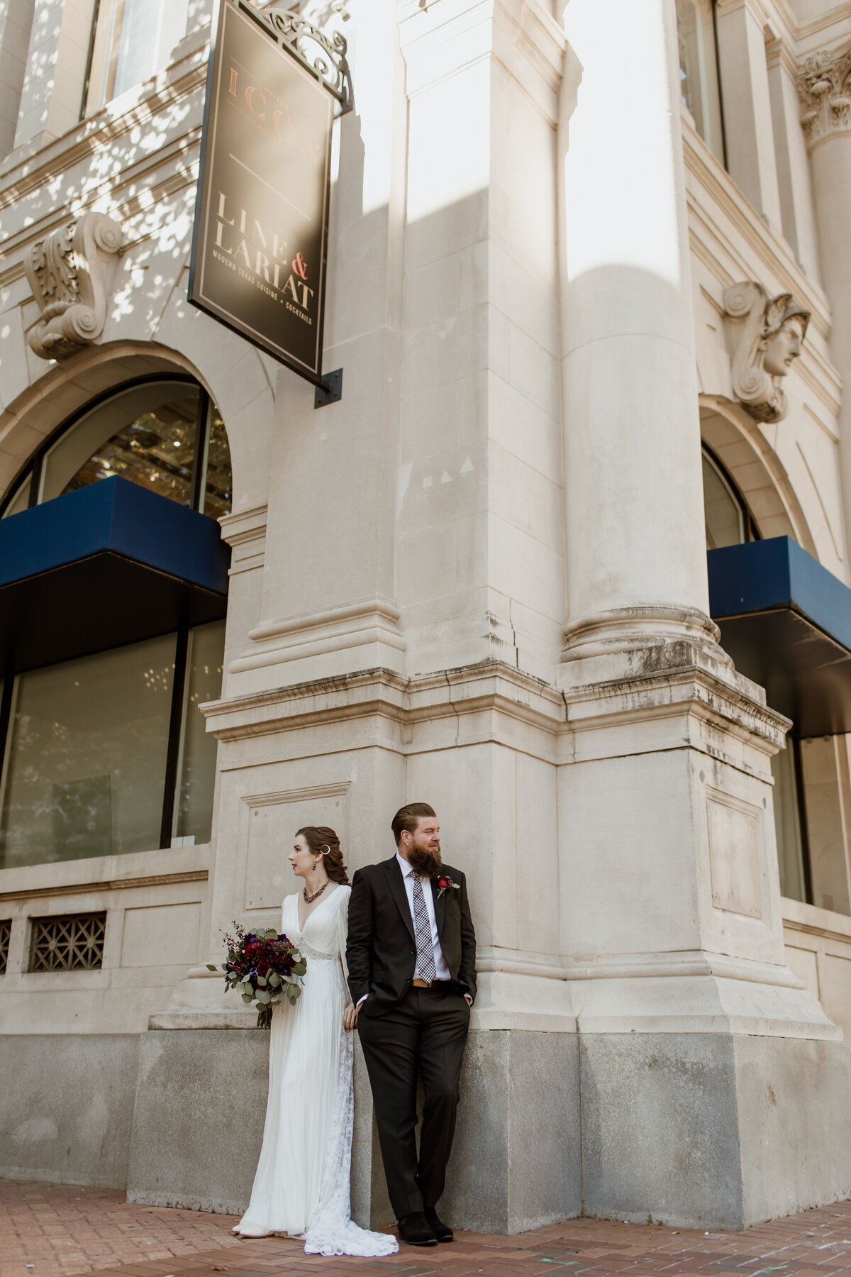 A bride and groom casually stand outside their hotel in downtown Houston Texas. Captured by Fort Worth Wedding Photographer, Megan Christine Studio