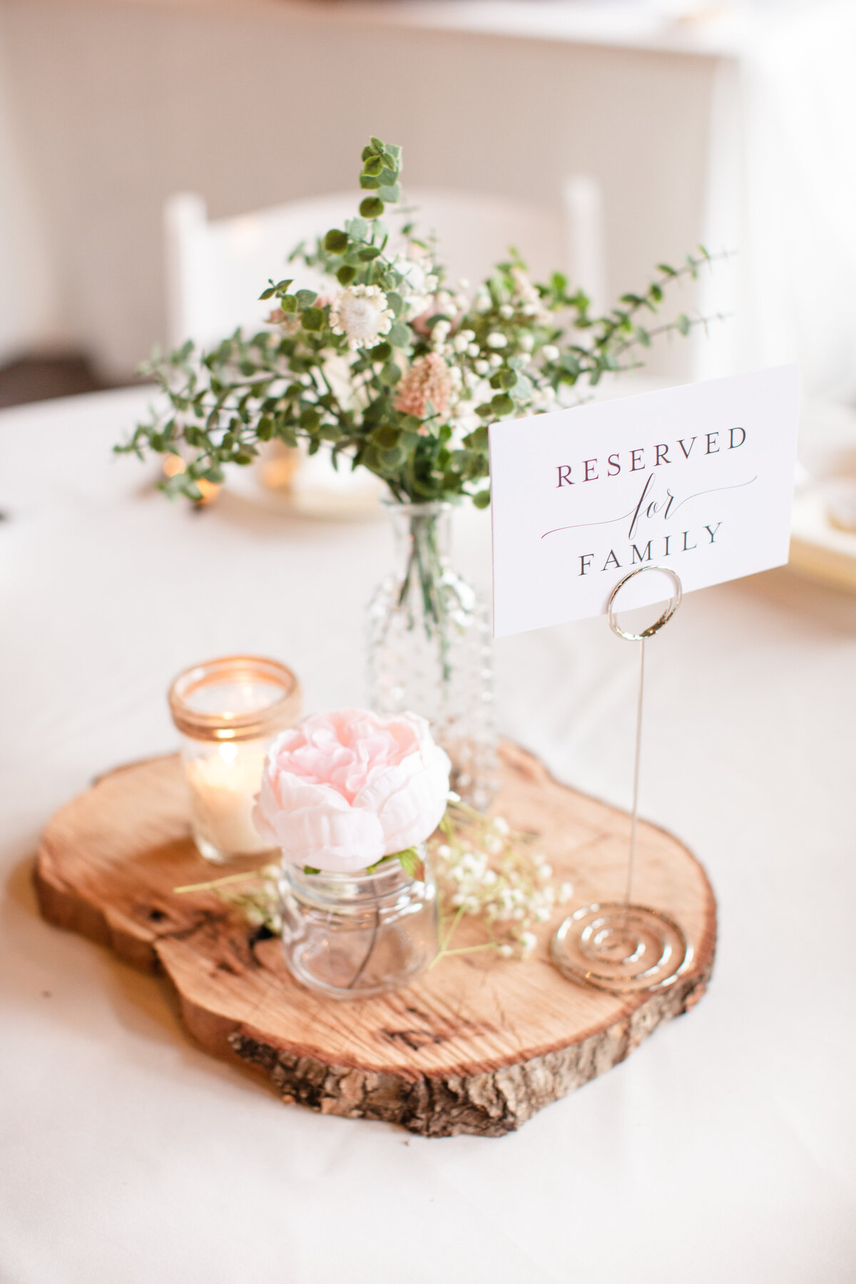 wood slice centerpiece with bud vase and reserved for family sign at Texas wedding