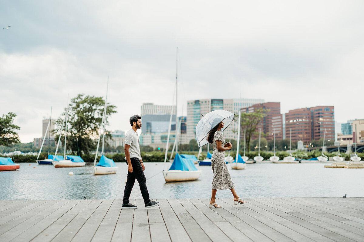 Engaged couple walks along Boston waterfront in the rain
