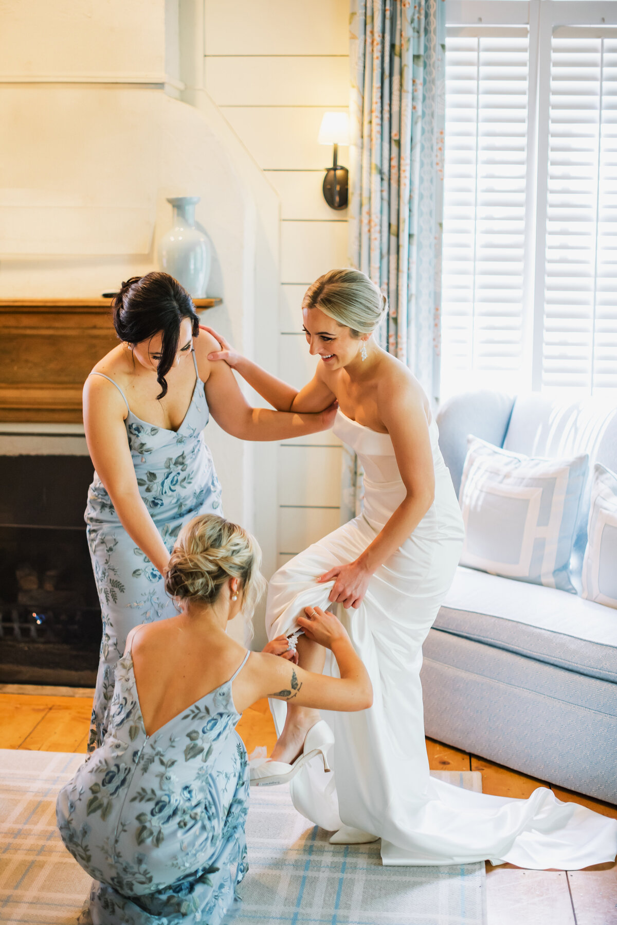 Bride getting ready at Old Edwards Inn in Highlands, NC with bridesmaids helping her into her shoes before the ceremony.
